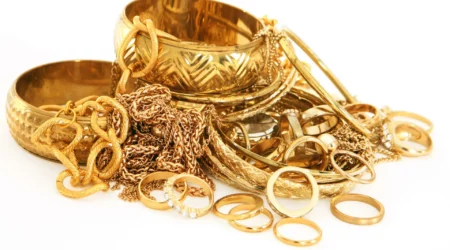 Scrap gold chains, rings, and other jewellery on white background
