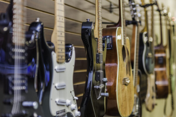 A closeup shot of the various types of guitars hanging on the wall in the music store